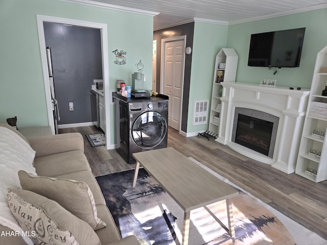 living room featuring washer / dryer, hardwood / wood-style flooring, and ornamental molding