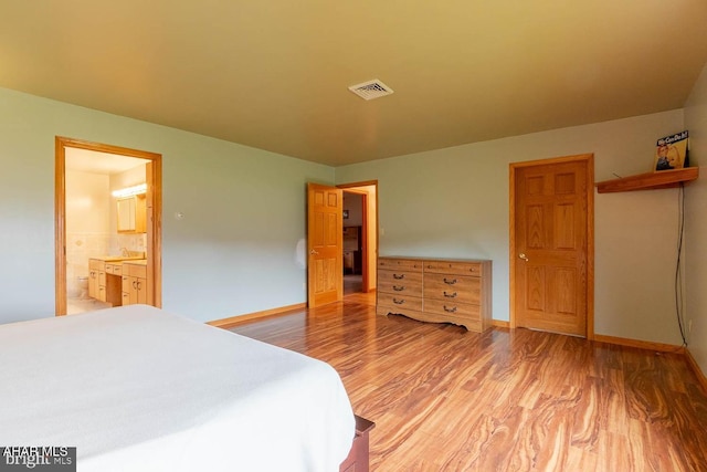 bedroom featuring hardwood / wood-style flooring and connected bathroom