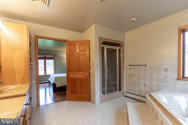 bathroom with tile walls, vanity, a baseboard radiator, tile patterned floors, and separate shower and tub