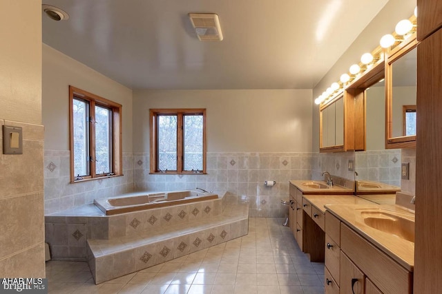 bathroom featuring tile patterned floors, tiled bath, tile walls, and vanity