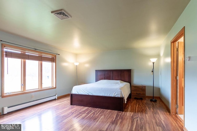 bedroom with a baseboard radiator and wood-type flooring