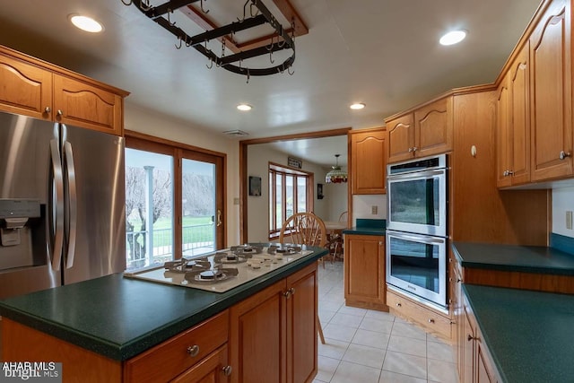 kitchen with stainless steel appliances, a kitchen island, and light tile patterned floors