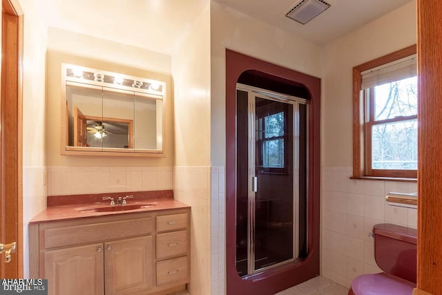 bathroom with vanity, toilet, an enclosed shower, and tile walls