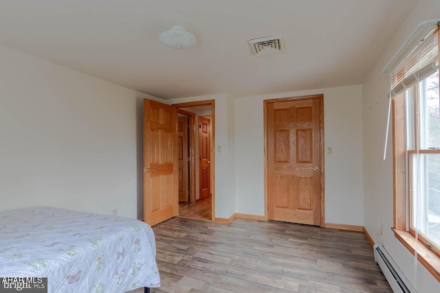 bedroom featuring light wood-type flooring and baseboard heating