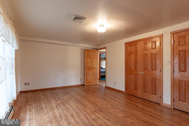 unfurnished bedroom with a baseboard radiator and light hardwood / wood-style flooring