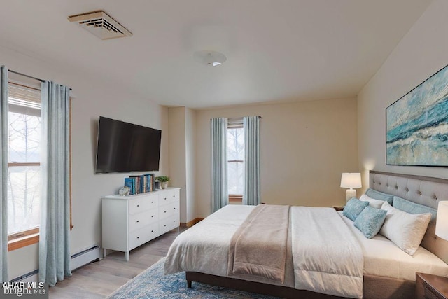 bedroom featuring baseboard heating and light hardwood / wood-style floors