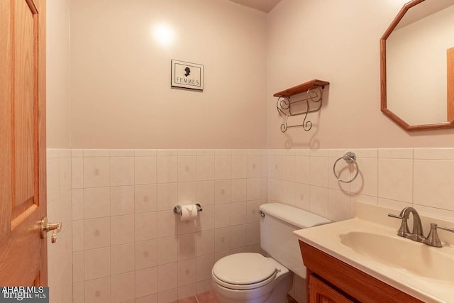 bathroom with vanity, toilet, and tile walls