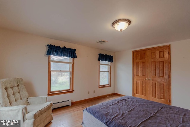 bedroom with a baseboard heating unit and light wood-type flooring