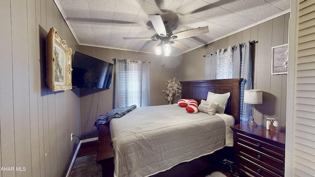 bedroom with multiple windows, wooden walls, ceiling fan, and crown molding