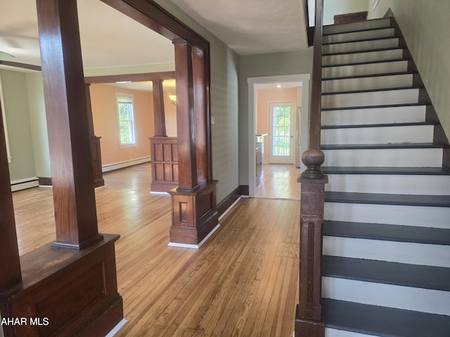 313 E John St, Bedford, PA 15522 - staircase featuring a baseboard radiator, ornate columns, a baseboard heating unit, and hardwood / wood-style flooring