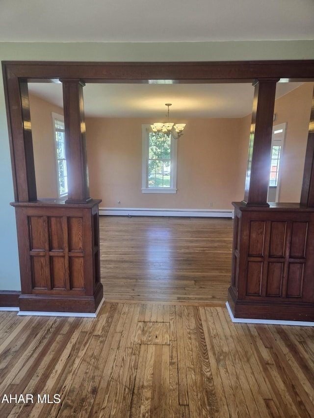 313 E John St, Bedford, PA 15522 - unfurnished dining area featuring wood finished floors, a chandelier, decorative columns, and a baseboard radiator