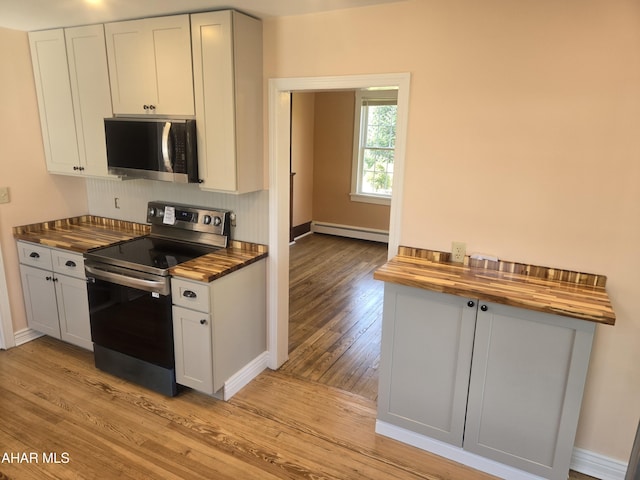 313 E John St, Bedford, PA 15522 - kitchen featuring appliances with stainless steel finishes, butcher block counters, a baseboard heating unit, light wood-style flooring, and backsplash