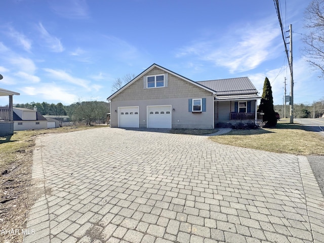 view of front of house featuring a front lawn, a porch, metal roof, decorative driveway, and an attached garage