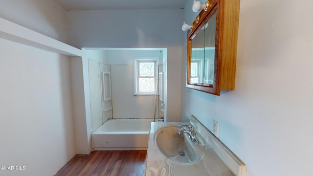 bathroom with washtub / shower combination, hardwood / wood-style floors, and vanity