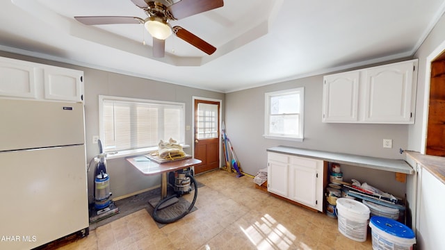 kitchen with white cabinetry, ceiling fan, white refrigerator, crown molding, and a tray ceiling