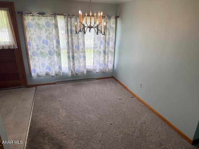 unfurnished dining area featuring baseboard heating, a chandelier, baseboards, and carpet floors