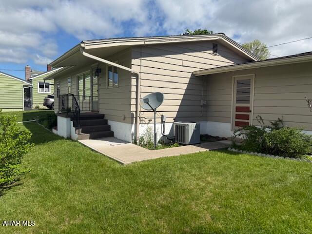 back of house featuring central AC unit and a lawn