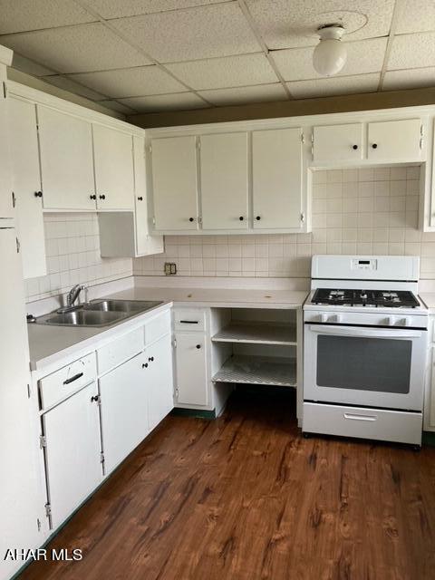 kitchen featuring dark hardwood / wood-style flooring, backsplash, sink, white range with gas stovetop, and white cabinetry