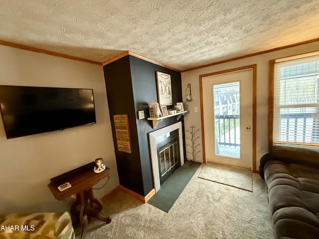 carpeted living area featuring ornamental molding, a glass covered fireplace, a textured ceiling, and baseboards