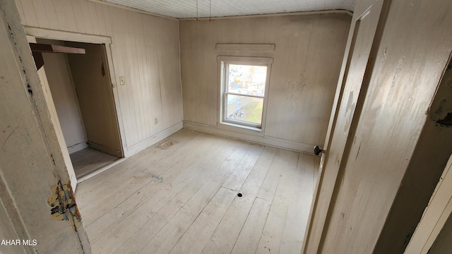 spare room with light hardwood / wood-style floors and wood walls