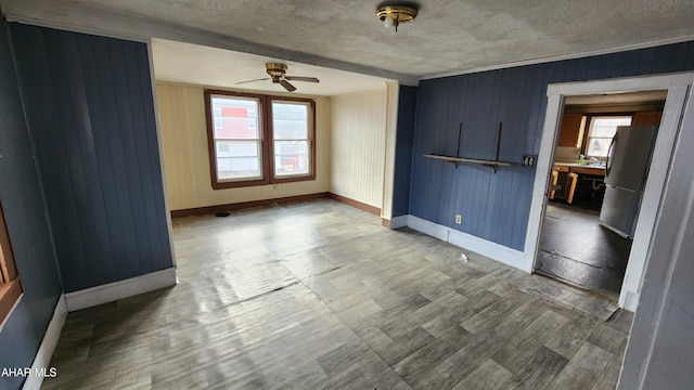 empty room with sink, wood walls, a textured ceiling, ceiling fan, and hardwood / wood-style floors