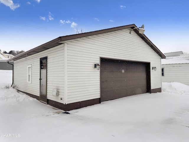 snow covered garage featuring a detached garage