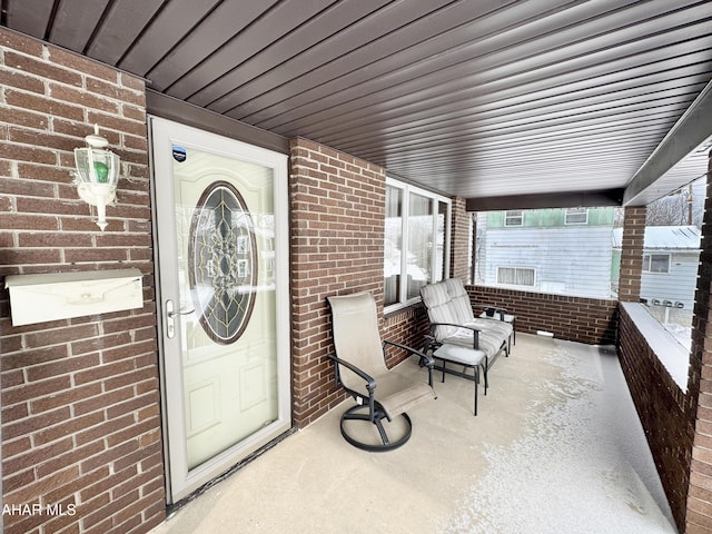 property entrance featuring covered porch and brick siding