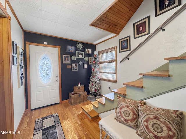 entrance foyer with lofted ceiling, baseboards, ornamental molding, stairway, and light wood finished floors