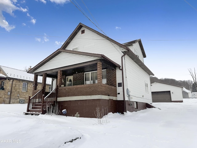 view of front facade with an outbuilding, a porch, brick siding, and a garage