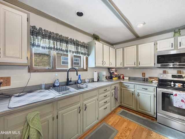 kitchen with stainless steel appliances, light wood-style flooring, a sink, and light countertops