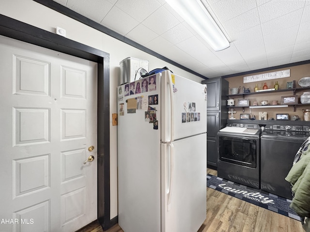 kitchen featuring open shelves, light wood-style flooring, washing machine and clothes dryer, and freestanding refrigerator