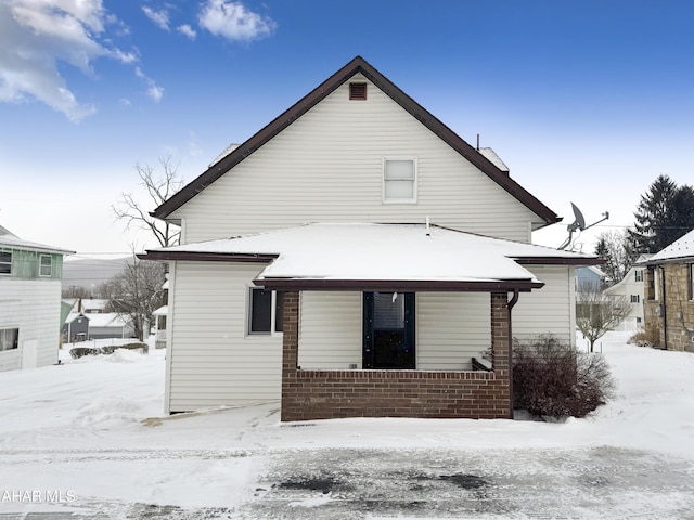 snow covered back of property with brick siding