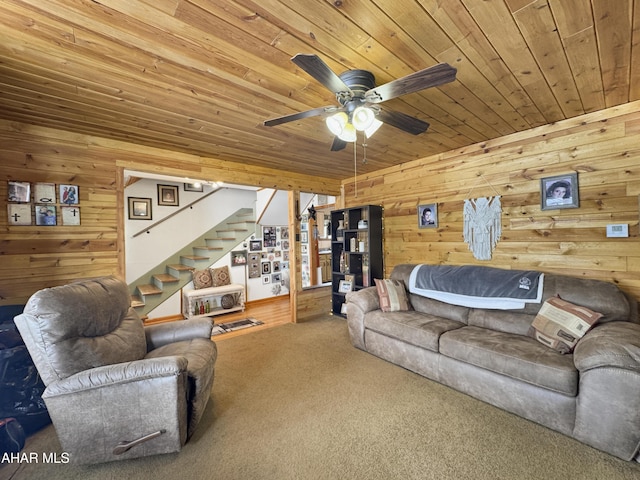 living area featuring wood ceiling, ceiling fan, stairway, carpet floors, and wood walls