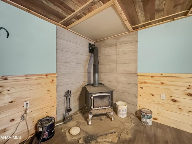 room details featuring concrete floors, a wood stove, and wood walls