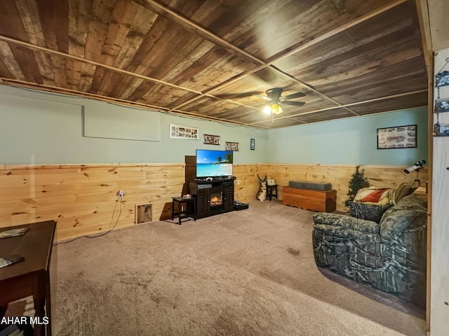 carpeted living room with wooden ceiling, ceiling fan, and wooden walls