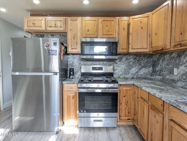 kitchen featuring backsplash, stainless steel appliances, stone counters, and light hardwood / wood-style flooring