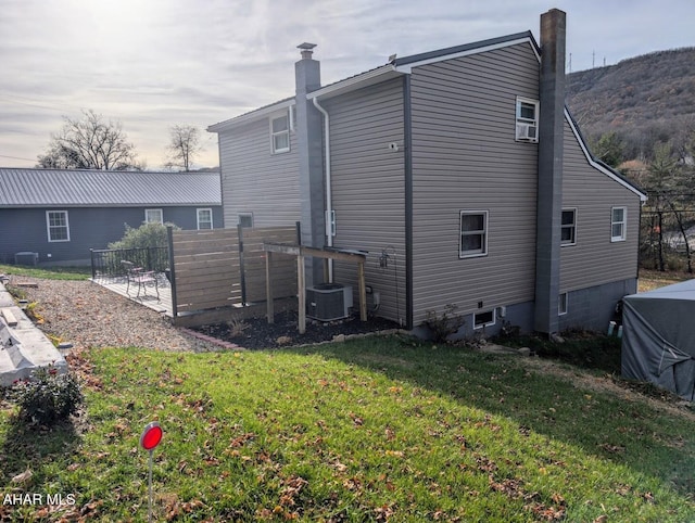 rear view of house featuring cooling unit and a lawn