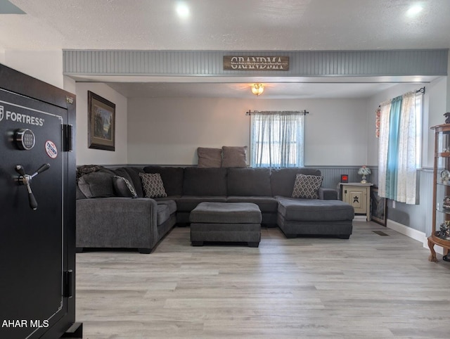 living room with a textured ceiling, light hardwood / wood-style flooring, and a wealth of natural light