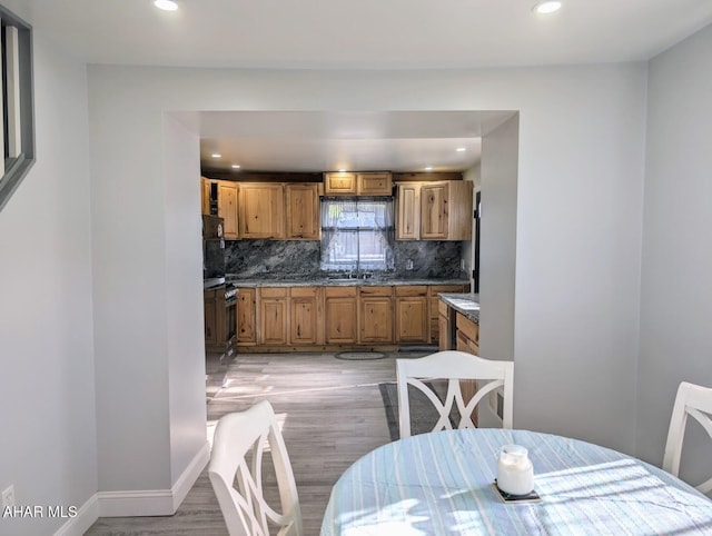 kitchen featuring oven, backsplash, and light hardwood / wood-style flooring