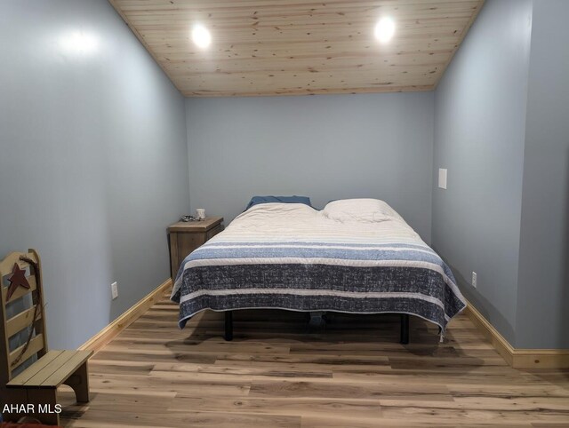 bedroom with hardwood / wood-style floors, vaulted ceiling, and wood ceiling