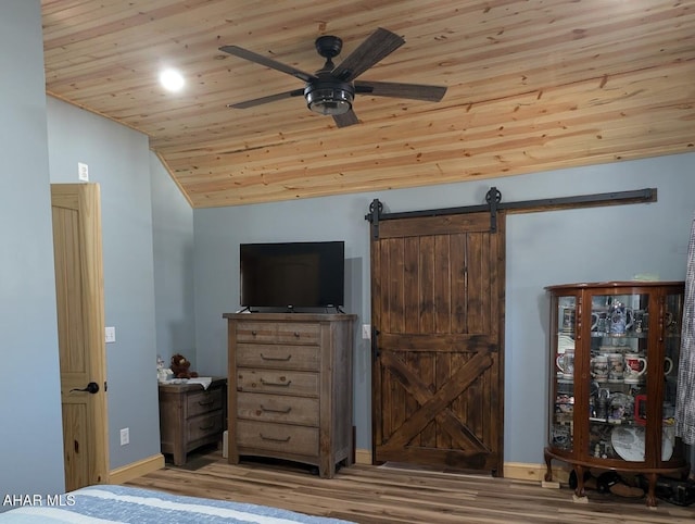 bedroom featuring vaulted ceiling, ceiling fan, a barn door, wooden ceiling, and light hardwood / wood-style floors