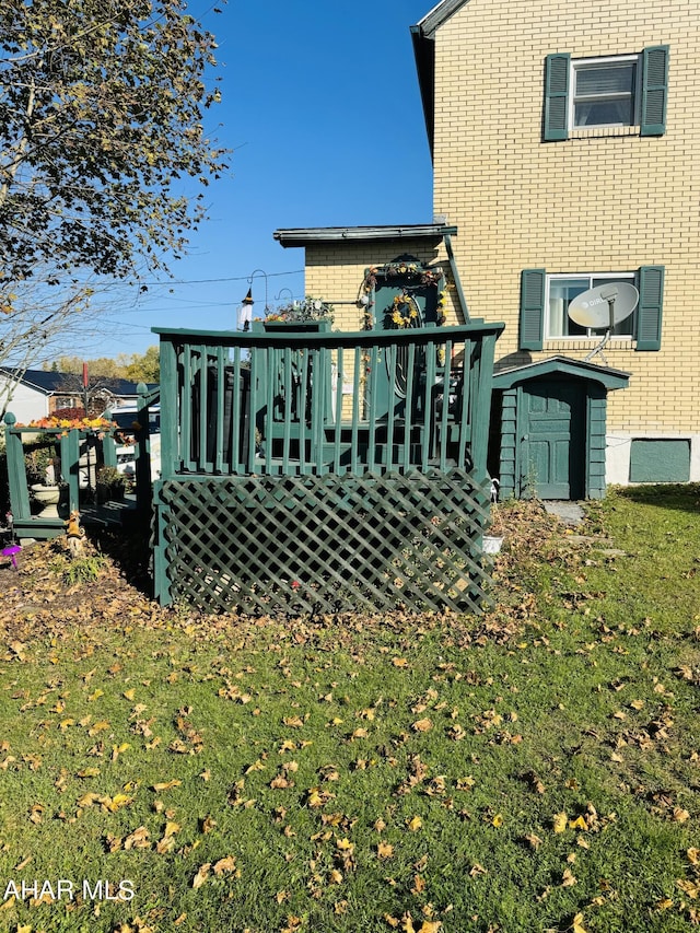 back of house featuring a storage shed, a yard, and a wooden deck