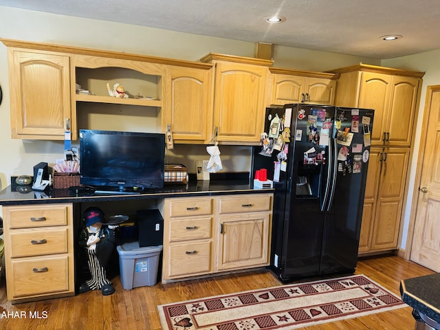 kitchen featuring hardwood / wood-style floors, light brown cabinets, and black fridge with ice dispenser