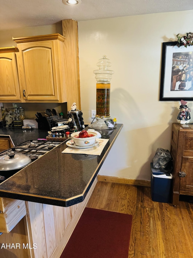 kitchen featuring kitchen peninsula, a kitchen breakfast bar, light brown cabinets, and dark hardwood / wood-style floors