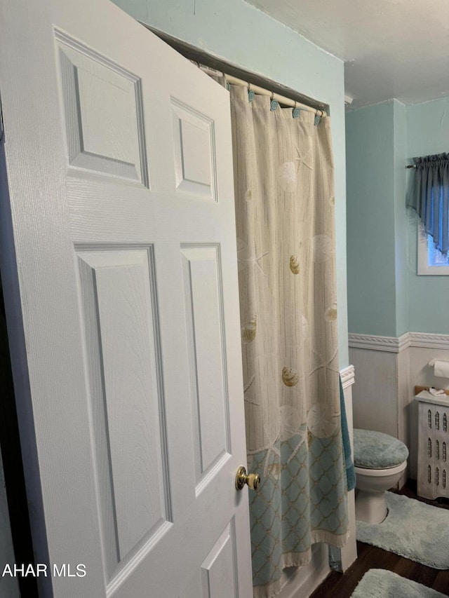 bathroom featuring hardwood / wood-style floors, toilet, and shower / bath combination with curtain