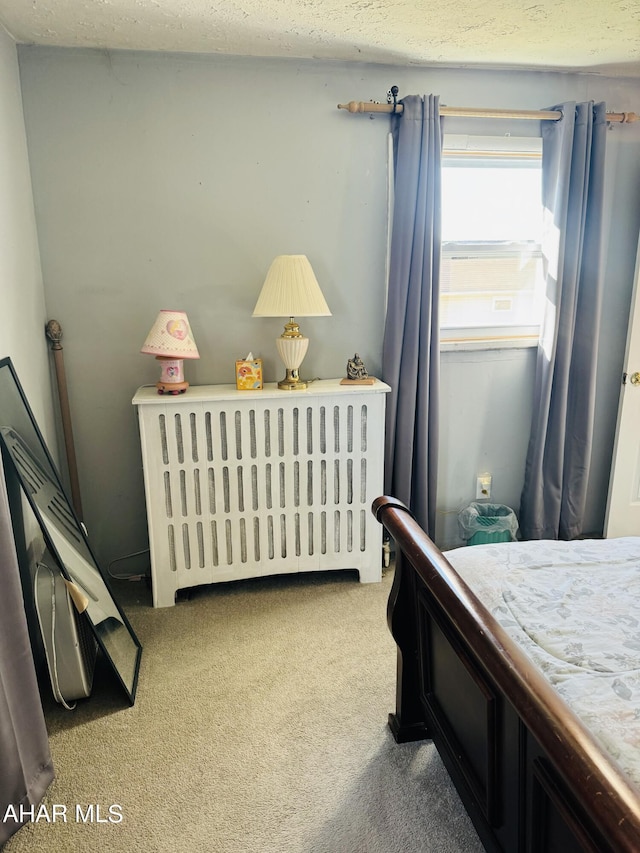 carpeted bedroom with radiator heating unit and a textured ceiling