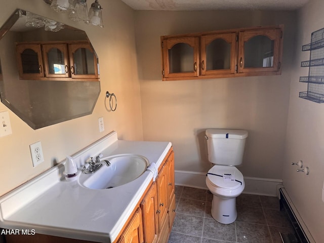 bathroom with tile patterned floors, vanity, a textured ceiling, baseboard heating, and toilet