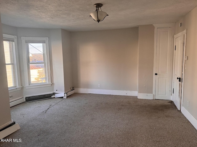 carpeted empty room with a textured ceiling and a baseboard heating unit