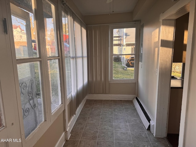 unfurnished sunroom featuring a wealth of natural light and a baseboard radiator