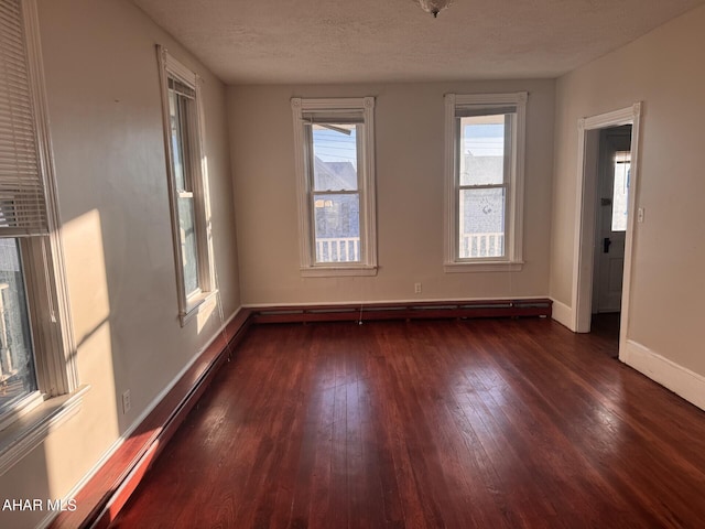 unfurnished room featuring a textured ceiling, dark hardwood / wood-style floors, and baseboard heating